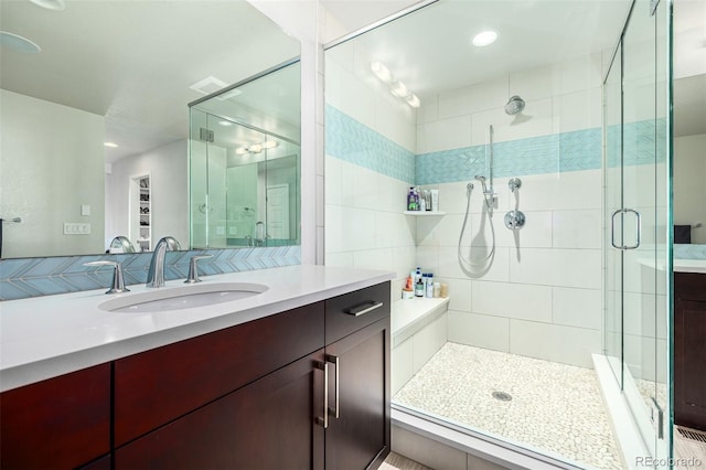 bathroom featuring a shower with shower door and vanity