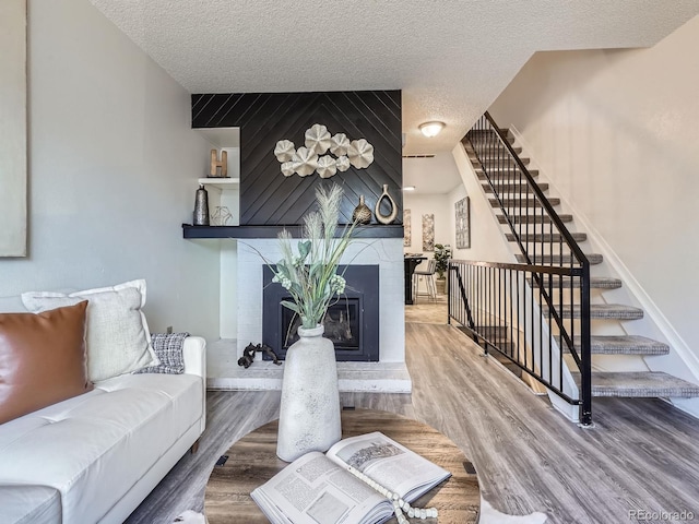 17681 E Loyola Dr Unit E, Aurora, CO 80013 - living area featuring a textured ceiling, stairs, a large fireplace, and wood finished floors