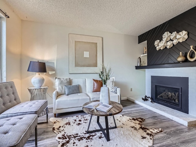 17681 E Loyola Dr Unit E, Aurora, CO 80013 - living room featuring a textured ceiling, wood finished floors, and a large fireplace