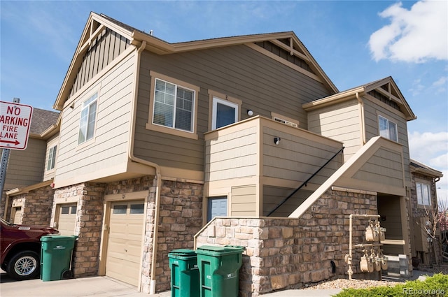 5732 S Addison Way # E, Aurora, CO 80016 - view of front facade with stone siding, board and batten siding, a garage, and driveway