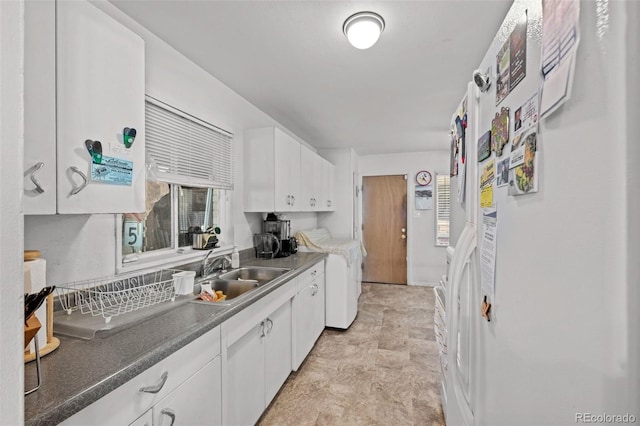 kitchen featuring white fridge with ice dispenser, white cabinets, washer / clothes dryer, and sink