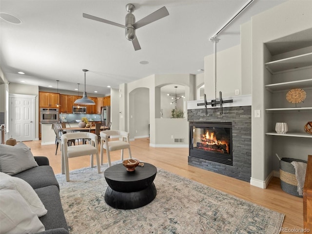 2821 Fulton St, Denver, CO 80238 - living room with ceiling fan, arched walkways, light wood-style flooring, recessed lighting, and a stone fireplace