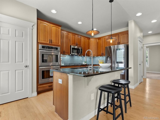 2821 Fulton St, Denver, CO 80238 - kitchen featuring stainless steel appliances, light wood finished floors, a kitchen breakfast bar, tasteful backsplash, and recessed lighting