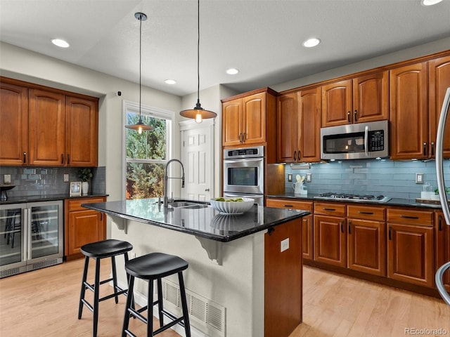 2821 Fulton St, Denver, CO 80238 - kitchen featuring wine cooler, appliances with stainless steel finishes, light wood-style floors, tasteful backsplash, and a kitchen island with sink