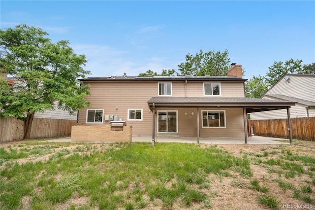1758 S Tucson St, Aurora, CO 80012 - rear view of house featuring a chimney, a patio area, a fenced backyard, and a carport