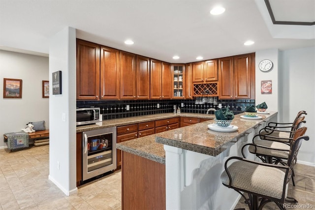 5810 Moss Ct, Golden, CO 80403 - kitchen featuring a breakfast bar, wine cooler, stainless steel microwave, backsplash, and recessed lighting
