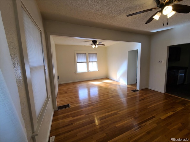 empty room with ceiling fan, dark hardwood / wood-style flooring, and a textured ceiling