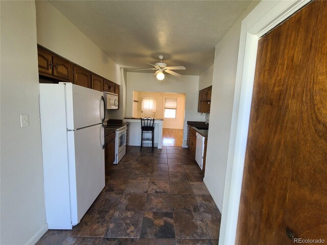 kitchen with white appliances, ceiling fan, and dark brown cabinetry