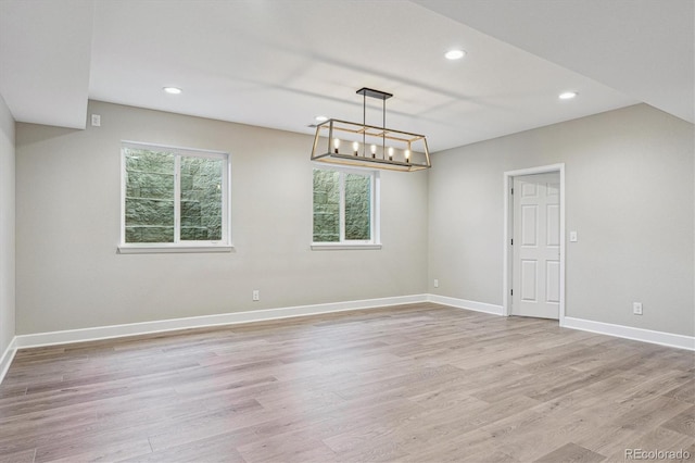 unfurnished room with recessed lighting, baseboards, a notable chandelier, and light wood-style flooring