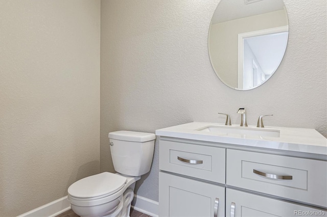 bathroom featuring toilet, baseboards, and vanity