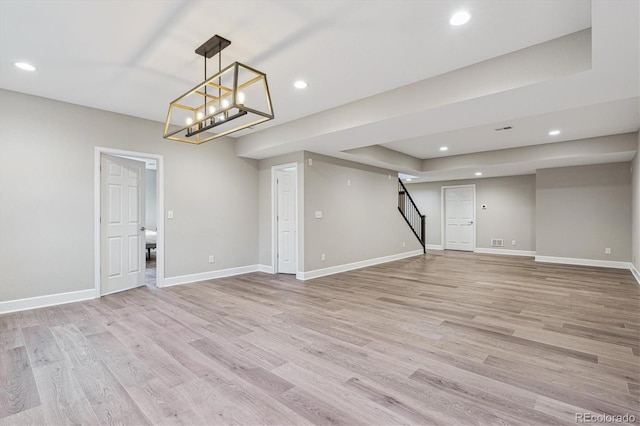 finished below grade area with recessed lighting, light wood-type flooring, and stairs
