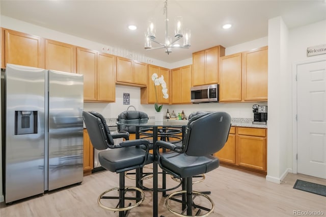 kitchen featuring light stone counters, a chandelier, light hardwood / wood-style floors, light brown cabinets, and stainless steel appliances