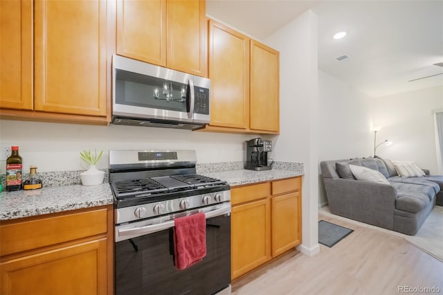 kitchen featuring appliances with stainless steel finishes, light hardwood / wood-style flooring, and light stone counters