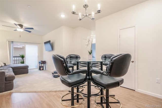 dining space featuring light carpet and ceiling fan with notable chandelier