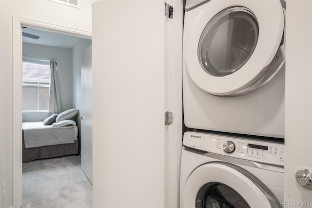 laundry area with stacked washer and clothes dryer and light carpet