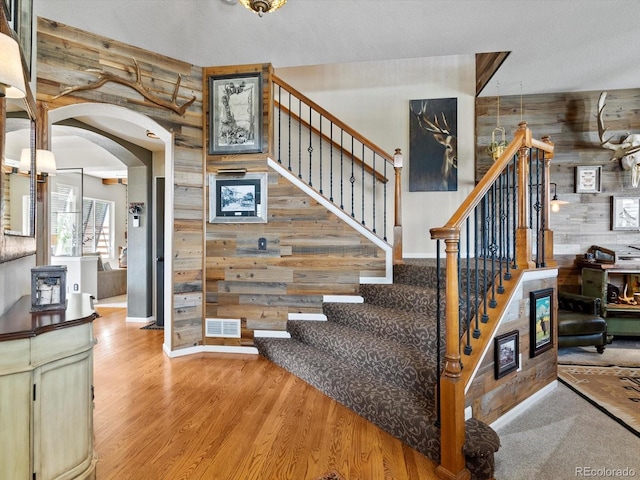 10273 Salida St, Commerce City, CO 80022 - stairs with wood walls, wood finished floors, visible vents, arched walkways, and baseboards
