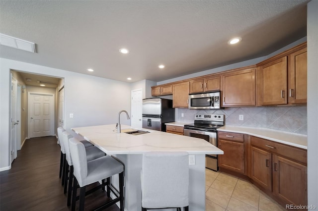 kitchen featuring sink, tasteful backsplash, a kitchen breakfast bar, an island with sink, and stainless steel appliances