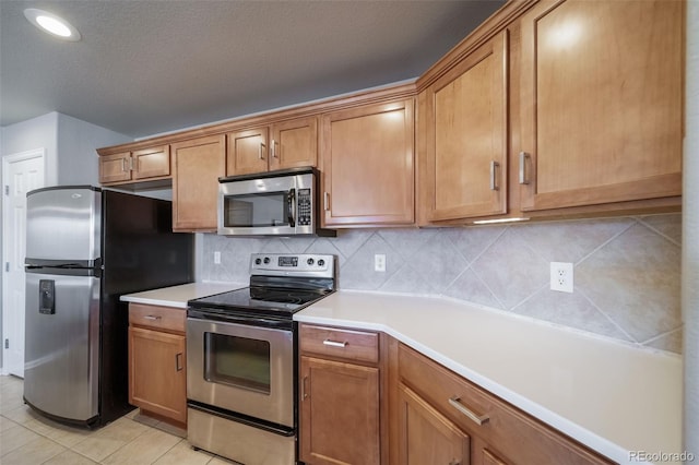 kitchen with tasteful backsplash, light tile patterned flooring, and appliances with stainless steel finishes