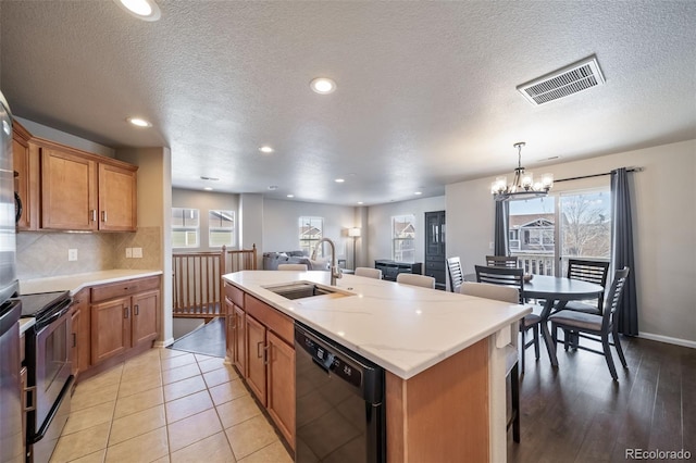 kitchen featuring sink, pendant lighting, dishwasher, an island with sink, and electric stove