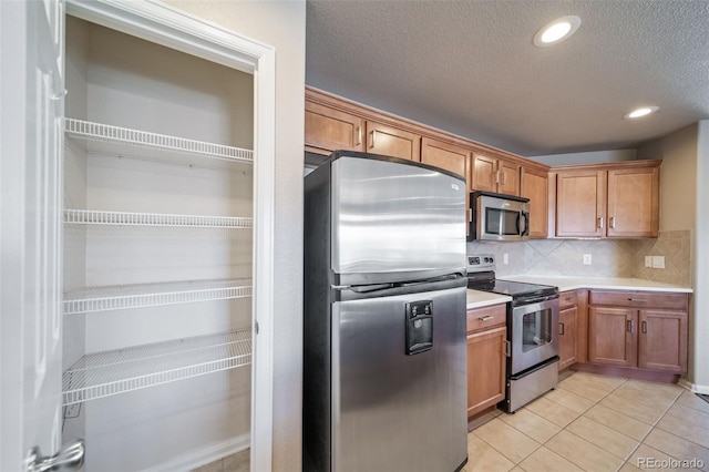 kitchen with stainless steel appliances, tasteful backsplash, light tile patterned floors, and a textured ceiling