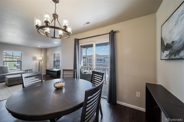 dining space with an inviting chandelier, plenty of natural light, dark hardwood / wood-style floors, and a textured ceiling