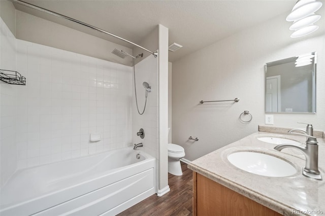 full bathroom featuring hardwood / wood-style flooring, bathing tub / shower combination, vanity, a textured ceiling, and toilet