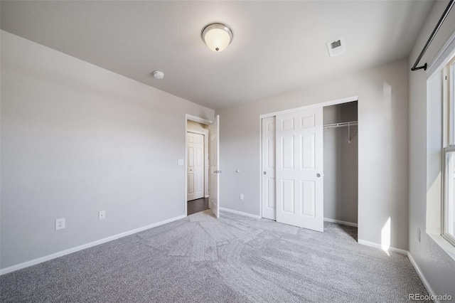 unfurnished bedroom with light carpet and a closet