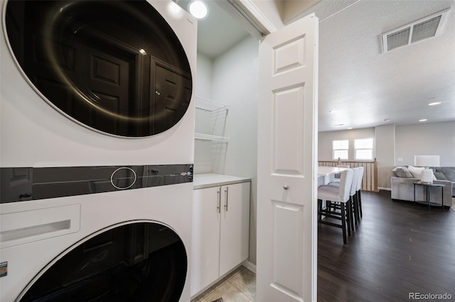 clothes washing area featuring wood-type flooring and stacked washing maching and dryer