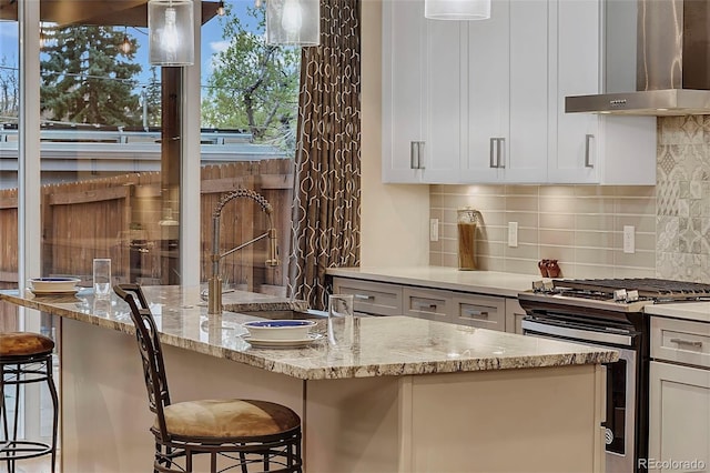 613 Iowa St, Golden, CO 80403 - kitchen featuring wall chimney exhaust hood, stainless steel range with gas cooktop, a sink, decorative backsplash, and light stone counters