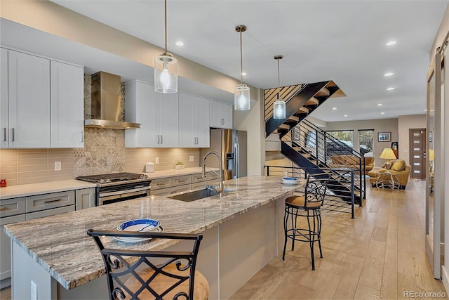 613 Iowa St, Golden, CO 80403 - kitchen with a kitchen breakfast bar, a sink, wall chimney exhaust hood, light wood-style flooring, and appliances with stainless steel finishes