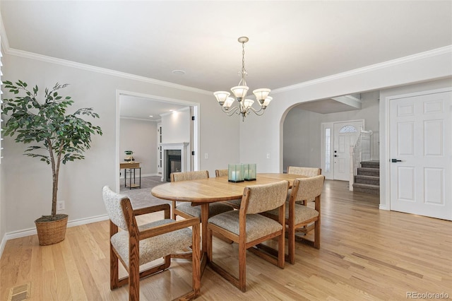 8474 E Otero Cir, Centennial, CO 80112 - dining area featuring arched walkways, light wood-type flooring, crown molding, a fireplace, and a chandelier