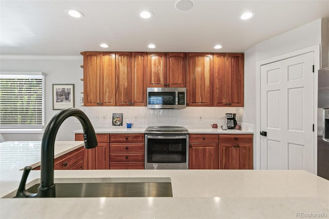 8474 E Otero Cir, Centennial, CO 80112 - kitchen with stainless steel appliances, a sink, light countertops, recessed lighting, and crown molding