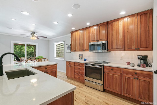 8474 E Otero Cir, Centennial, CO 80112 - kitchen featuring stainless steel appliances, a sink, crown molding, light wood-style floors, and light countertops