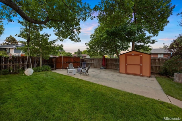 13693 W Utah Cir, Lakewood, CO 80228 - yard at dusk featuring a patio, a storage unit, and a fenced backyard
