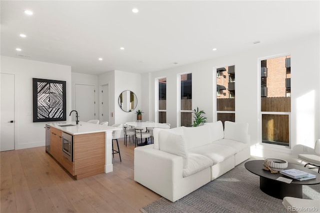 living room featuring light hardwood / wood-style floors, sink, and a wealth of natural light