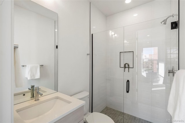 bathroom with walk in shower, vanity, and toilet