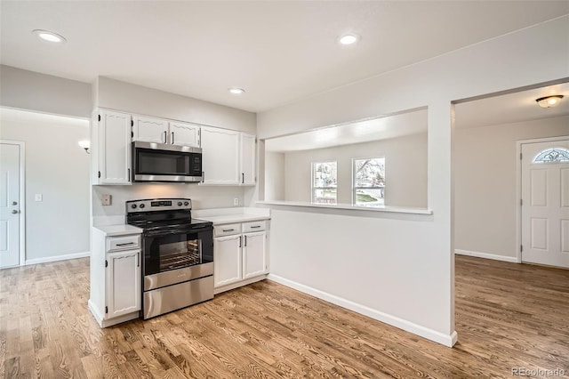kitchen with light countertops, white cabinetry, light wood-style flooring, baseboards, and appliances with stainless steel finishes