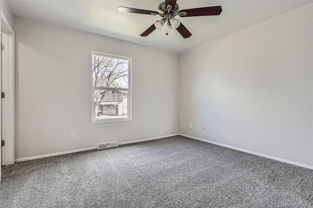 empty room with carpet floors, a ceiling fan, visible vents, and baseboards
