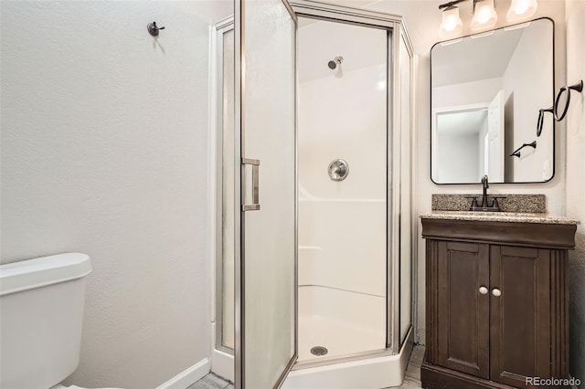 full bath with baseboards, toilet, vanity, and a stall shower