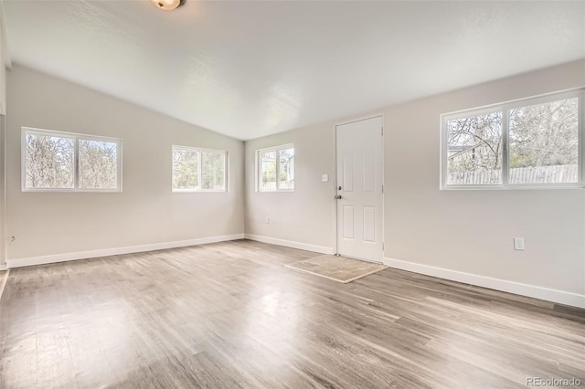 interior space with baseboards, vaulted ceiling, and wood finished floors