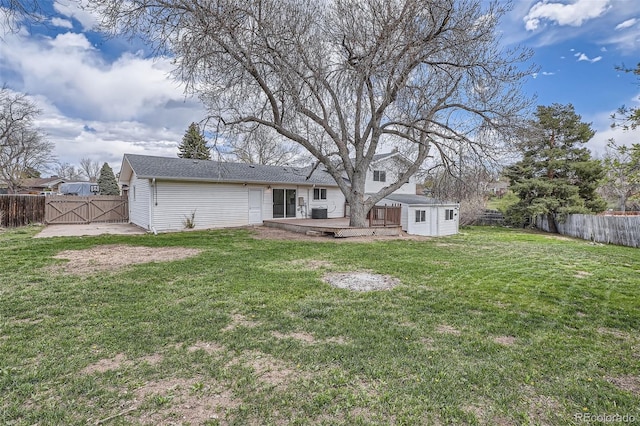 rear view of property featuring a fenced backyard, a gate, a yard, and a wooden deck