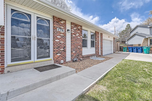 entrance to property with brick siding, french doors, and an attached garage
