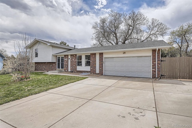 split level home with a front lawn, concrete driveway, fence, brick siding, and a garage