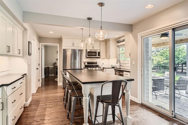 7708 S Krameria Ct, Centennial, CO 80112 - kitchen featuring stainless steel appliances, dark countertops, a breakfast bar area, dark wood-type flooring, and decorative backsplash