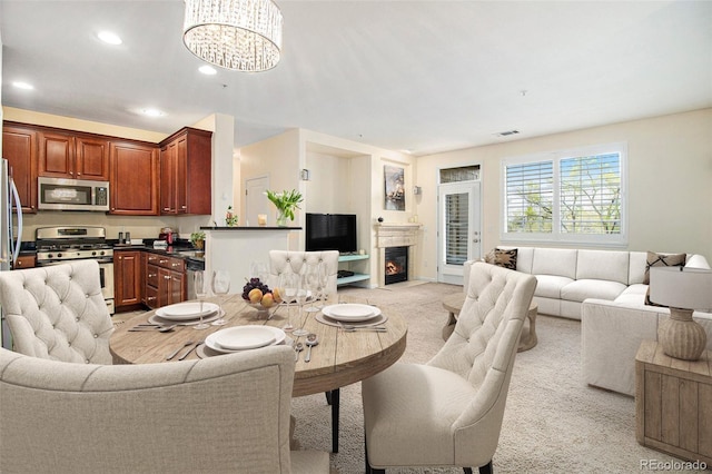 dining room with an inviting chandelier, visible vents, recessed lighting, light colored carpet, and a fireplace with flush hearth