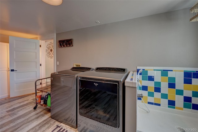 laundry room featuring washer and clothes dryer and light hardwood / wood-style floors