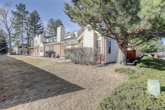 view of home's exterior featuring central AC unit, fence, and brick siding