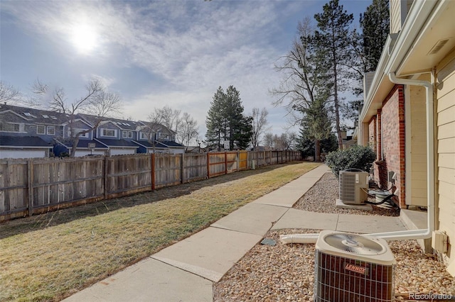 view of yard featuring a fenced backyard, a residential view, and central AC