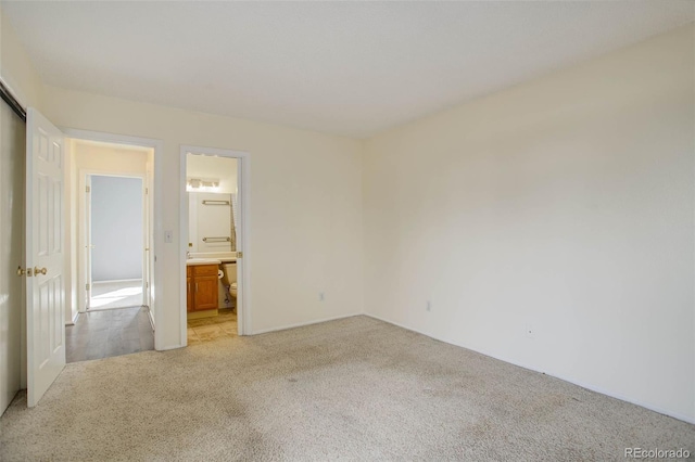 unfurnished bedroom with light colored carpet and ensuite bath