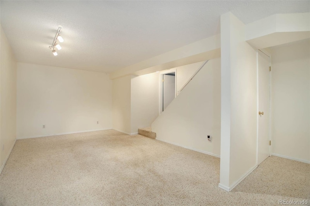 finished basement featuring stairway, carpet flooring, a textured ceiling, and baseboards